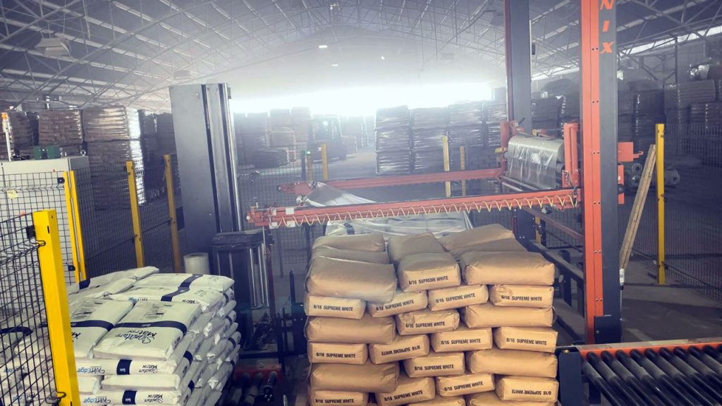 automatic stretch wrapper applying hood to pallet with bags